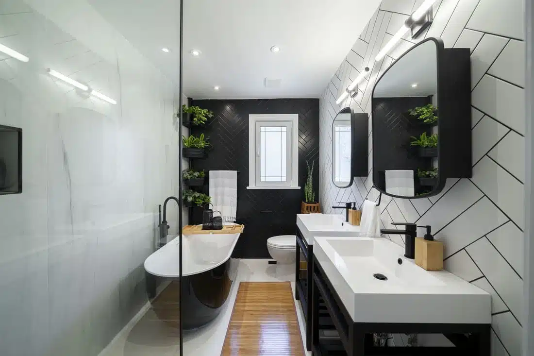 Modern black and white bathroom renovation featuring a freestanding tub, herringbone tile, and contemporary fixtures